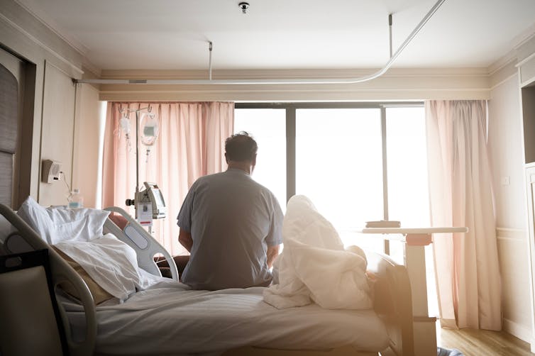 A patient sitting in a hospital bed, seen from behind